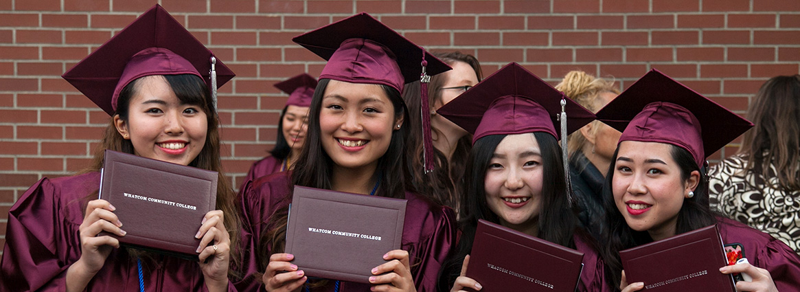 Four graduating students smiling in cap and gowns