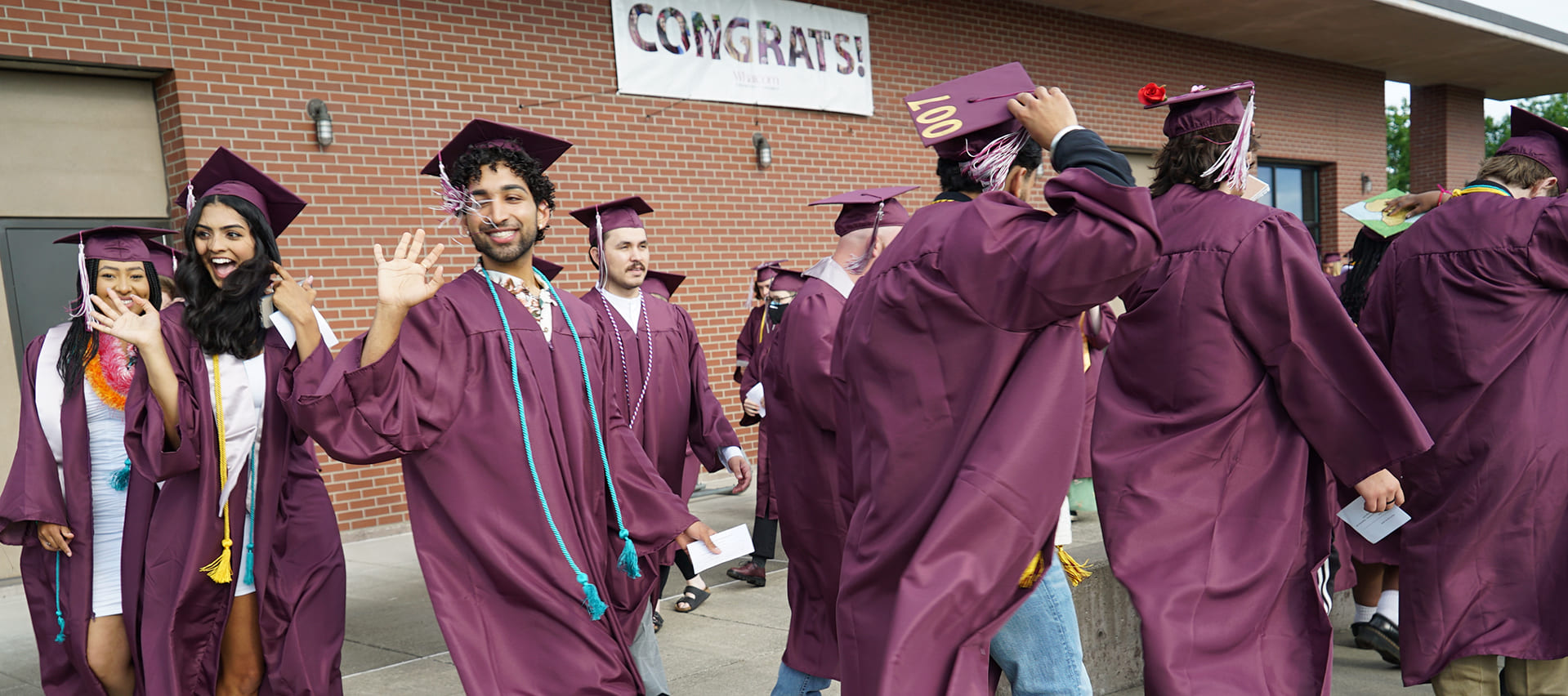 Graduates smiling and waving in their caps and gowns