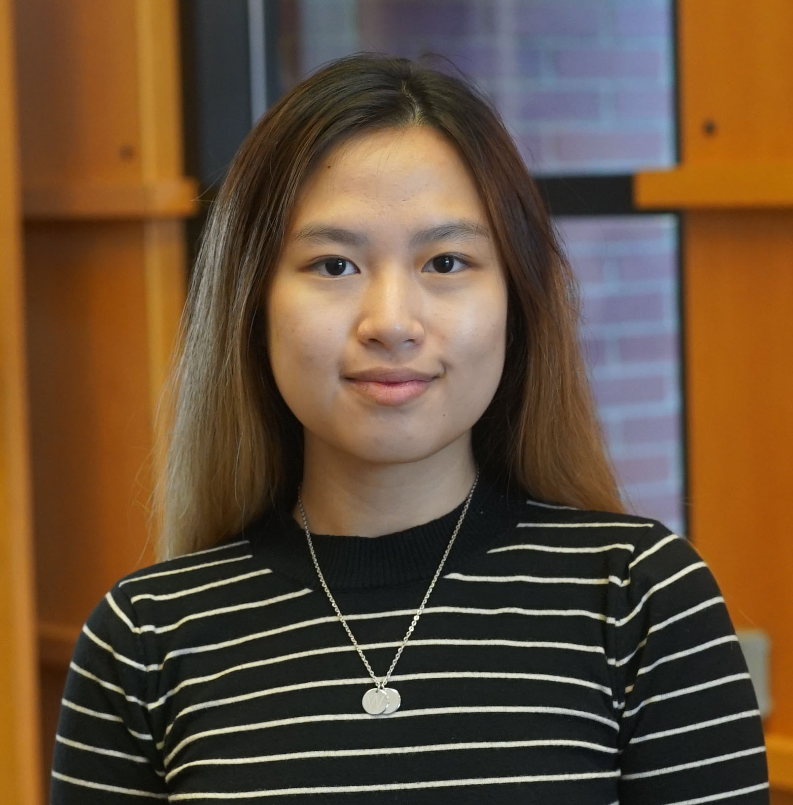 Headshot of Jovanka. She is standing in the Heiner Foyer wearing a stiped shirt 