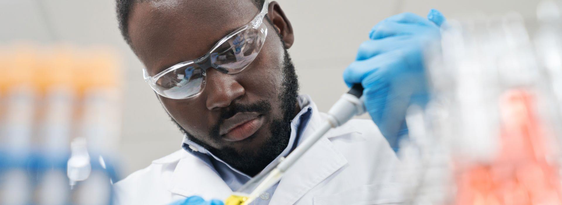 Man with lab gear using pipette