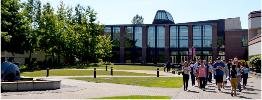 Students walking by the Gathering fountian with the Syre Student Center in the background