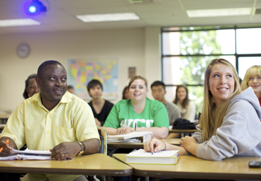 Students in class smiling and looking at board